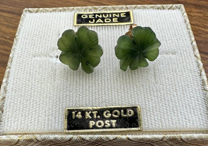 Genuine jade shamrock earrings with 14 karat gold posts on a textured jewelry box.