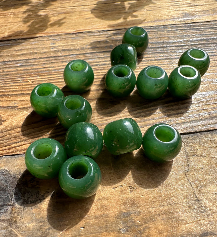Green round beads with central holes scattered on a weathered wooden surface