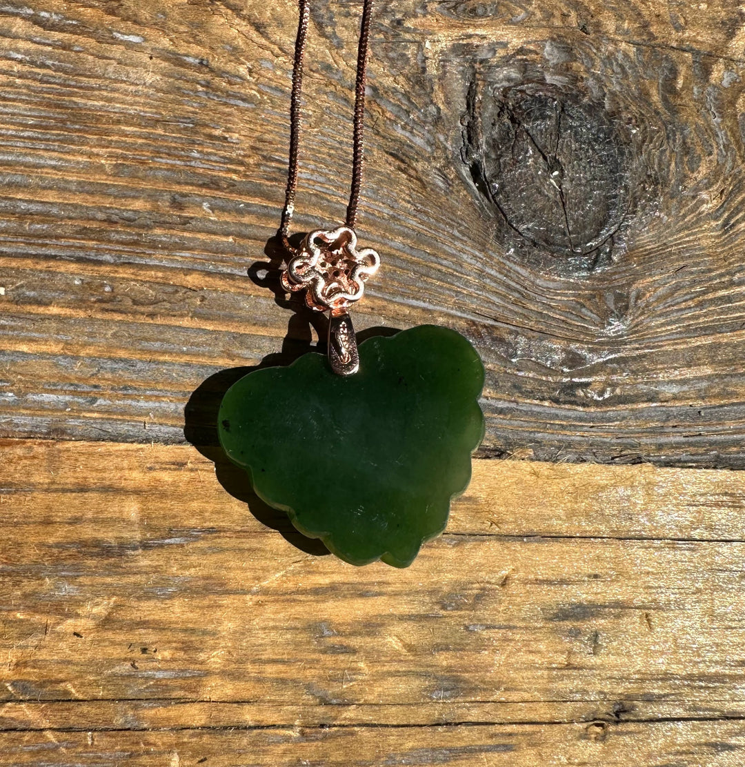 Dark green nephrite jade butterfly pendant on copper chain displayed on rustic wood