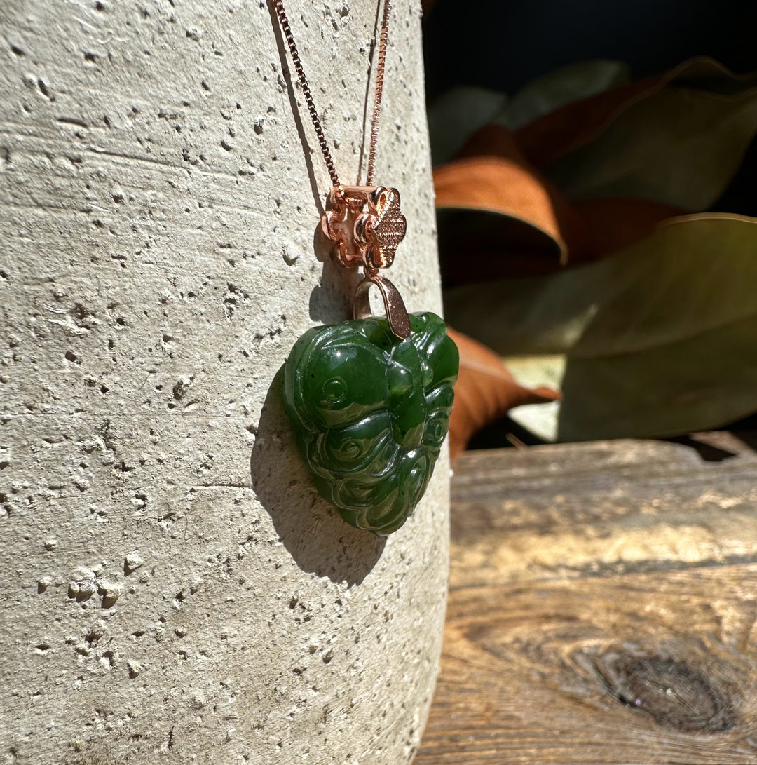 Close-up of dark green nephrite jade butterfly pendant on copper chain with a decorative flower bail.