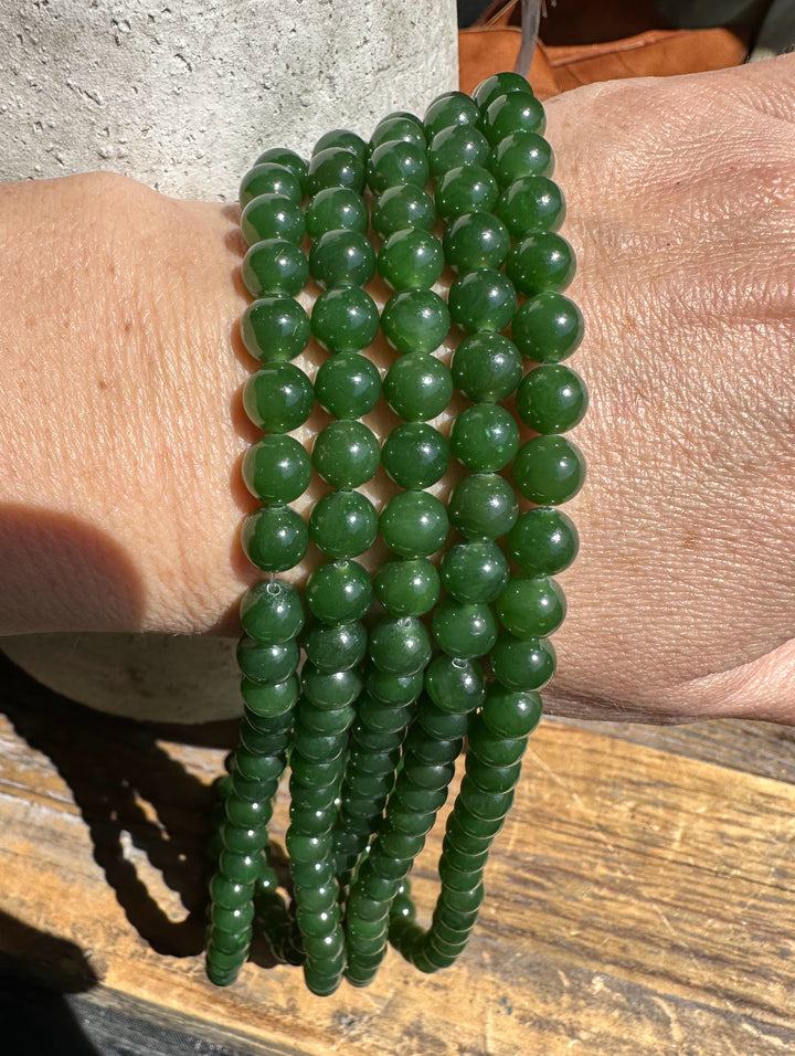 Multiple strands of seven millimeter nephrite jade beads wrapped around a wrist.