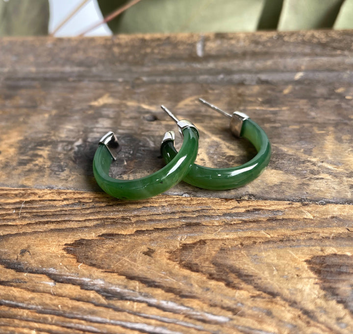 Green Canadian Jade hoop earrings with stainless posts on a rustic wooden surface