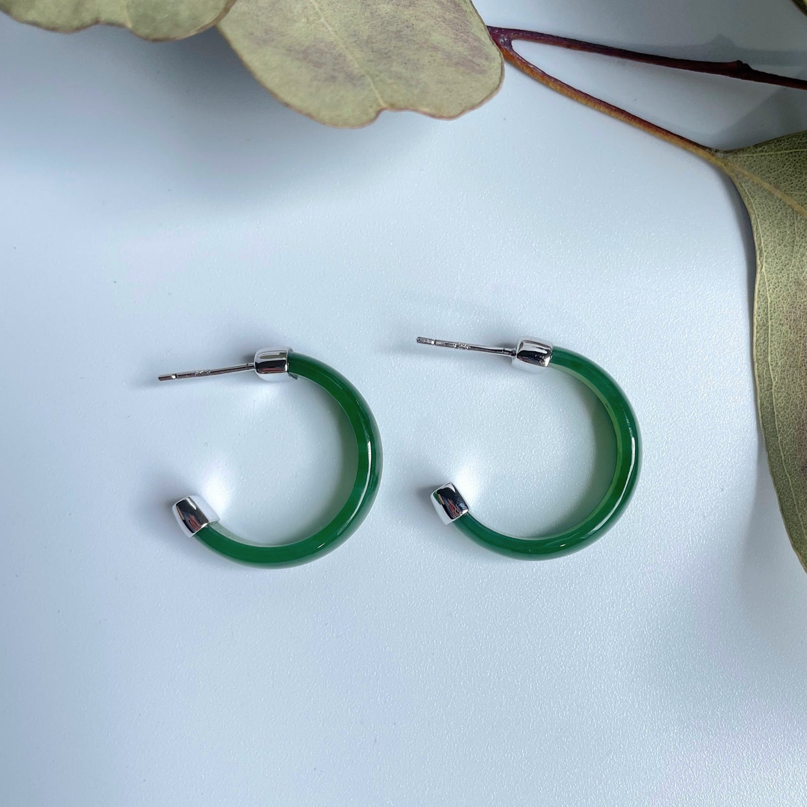 Green Canadian Jade hoop earrings with silver end caps on a white background