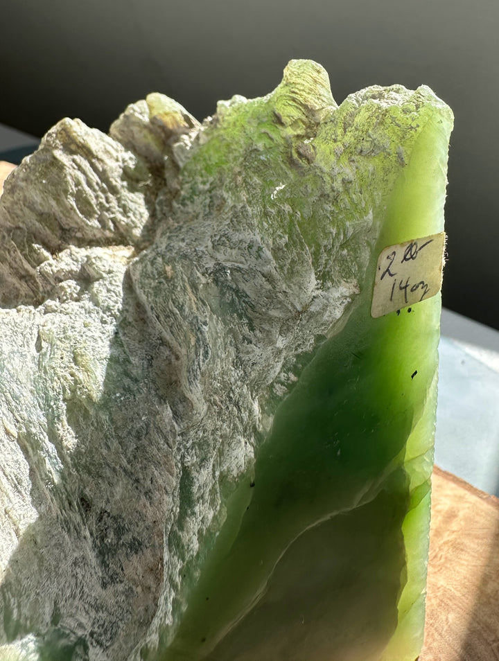 Rough Siberian light green nephrite jade specimen with gray matrix and bright green edge