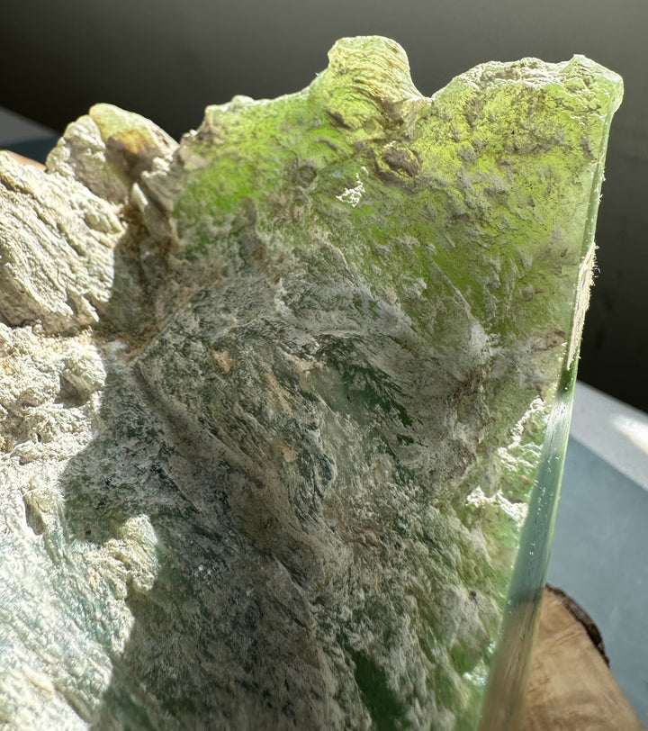 Rough nephrite jade specimen showing bright green patches on gray rocky matrix