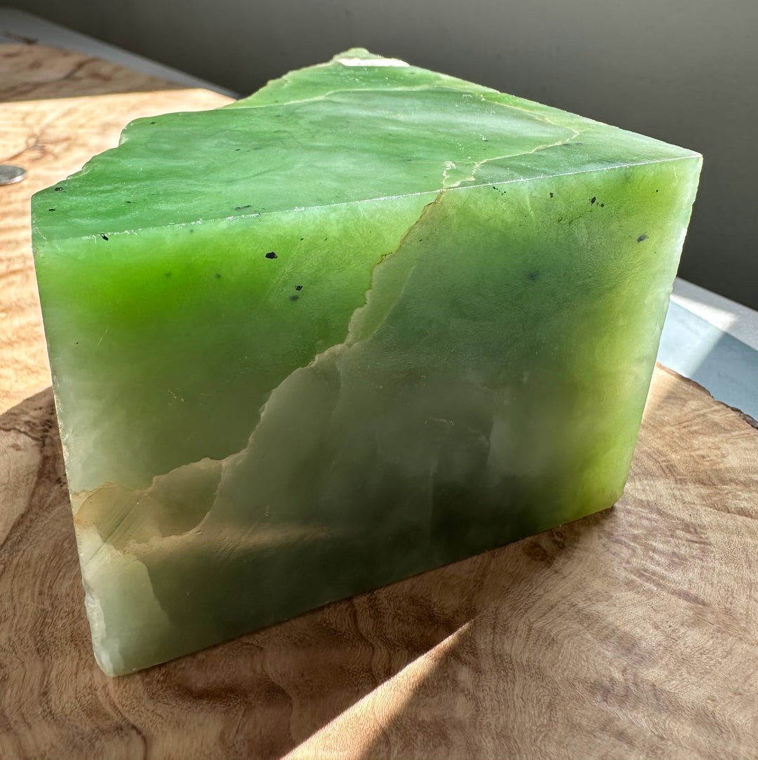 Rectangular nephrite jade slab with vibrant green surface and a rough jagged top edge