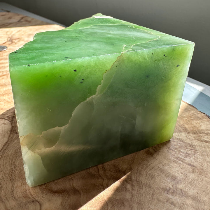 Rectangular nephrite jade slab with vibrant green surface and a rough jagged top edge