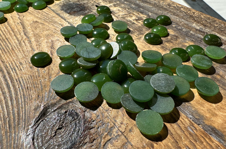 Close up of flat-backed green 9mm round cabochons on weathered wood