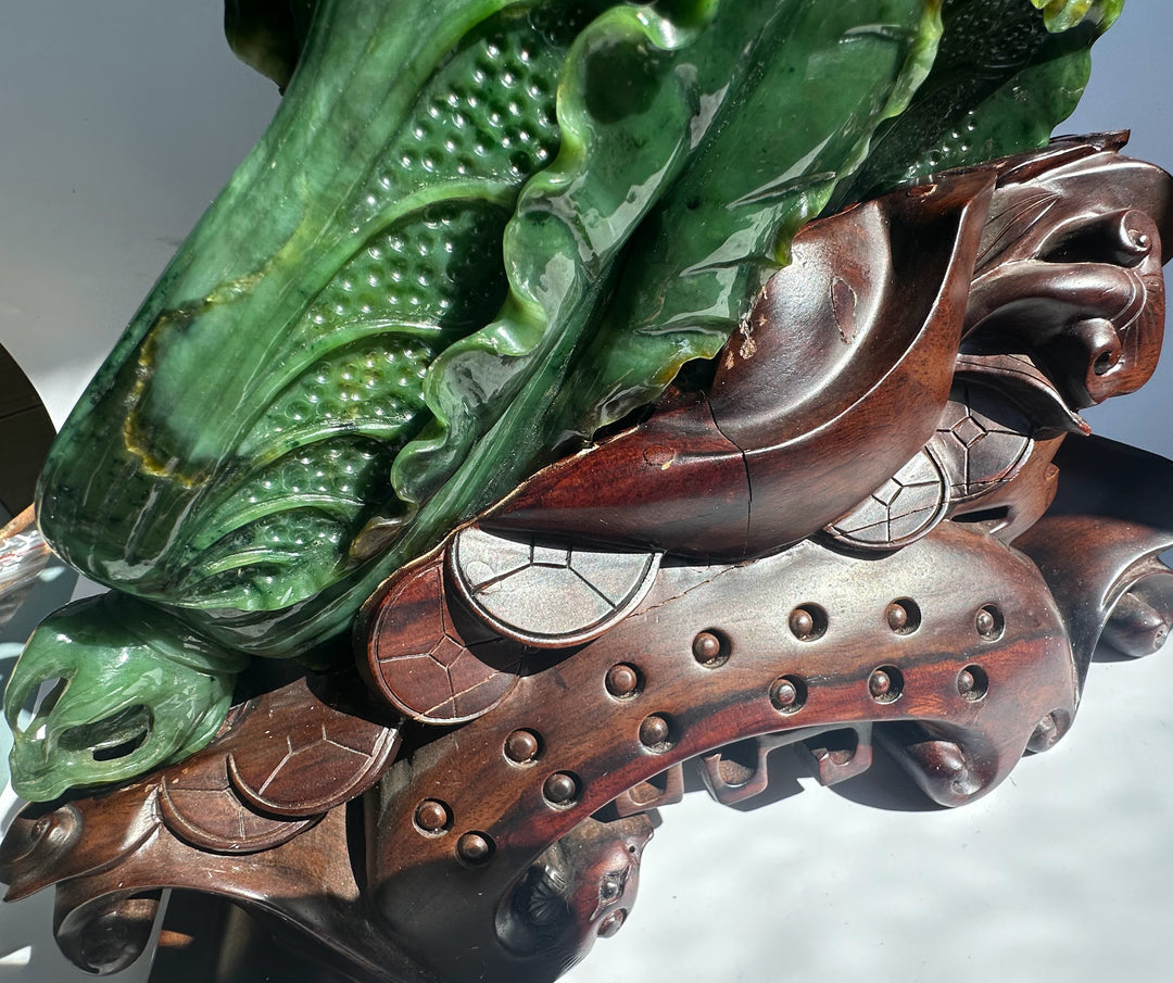 Hand carved large Canadian jade Chinese cabbage sculpture resting on an ornate wooden base.