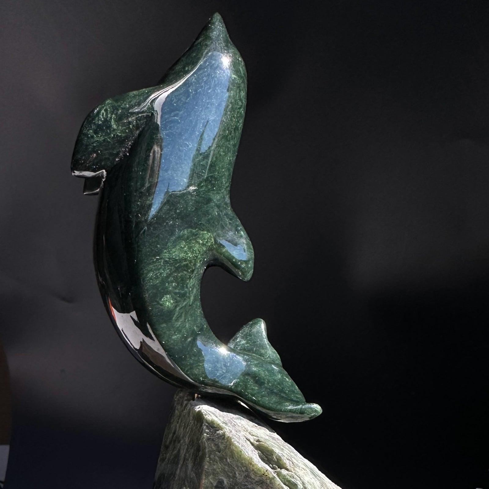Dark green Canadian jade dolphin carved on a jade base.