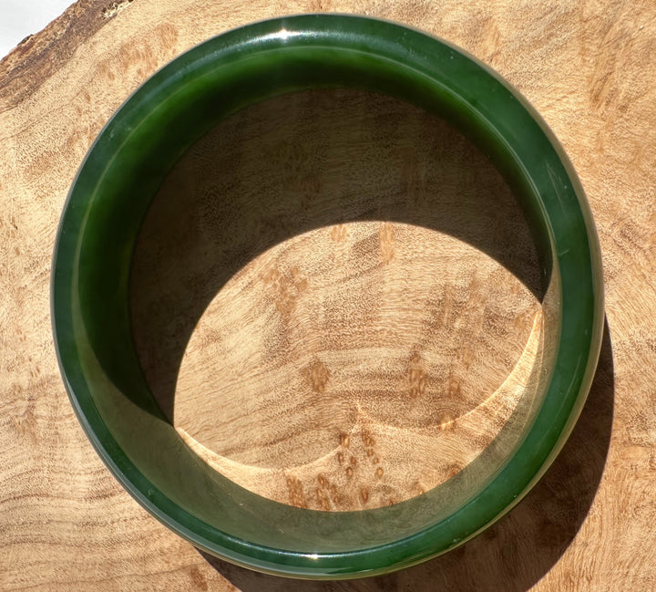 Canadian nephrite jade bangle in deep green viewed from above on a wooden surface