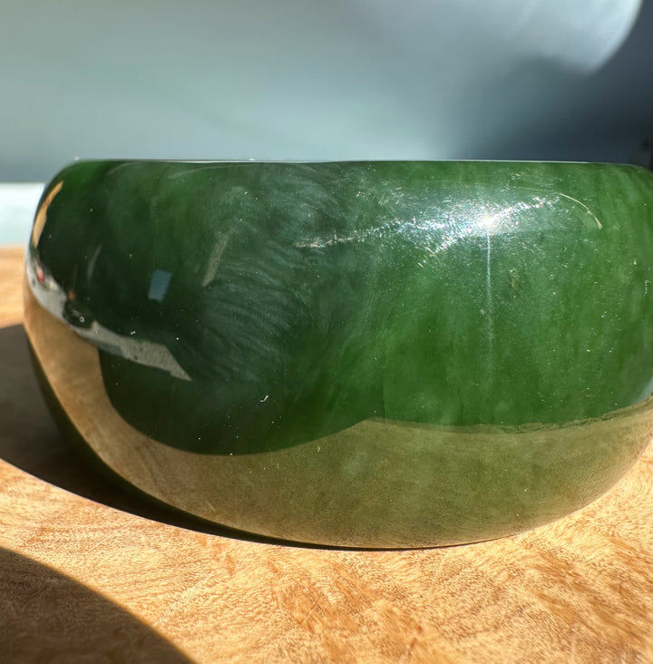 Side view of Wide Cassiar Jade Bangle showing thick rounded band in rich green jade.