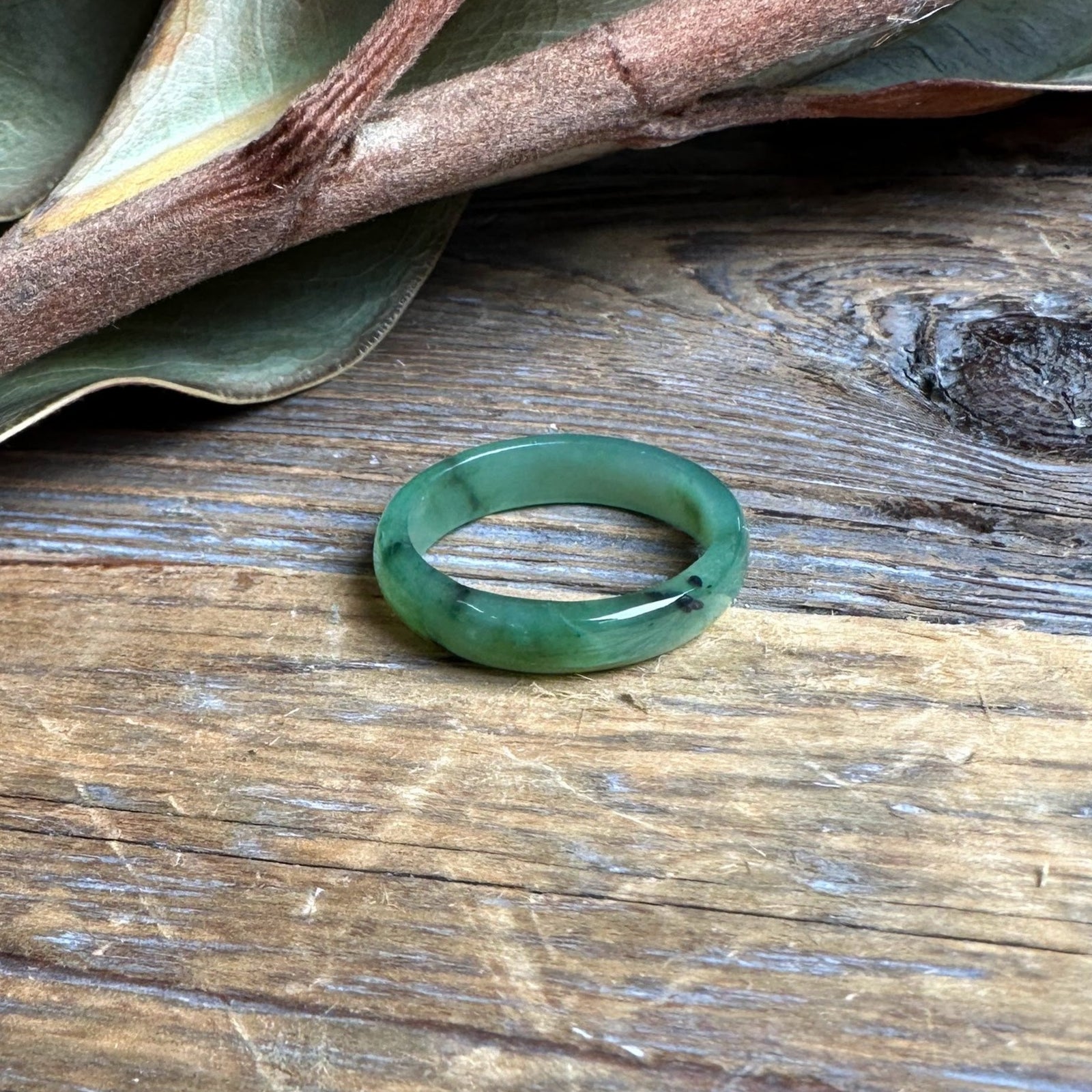 Narrow jade band ring 5mm resting on a rustic wooden surface