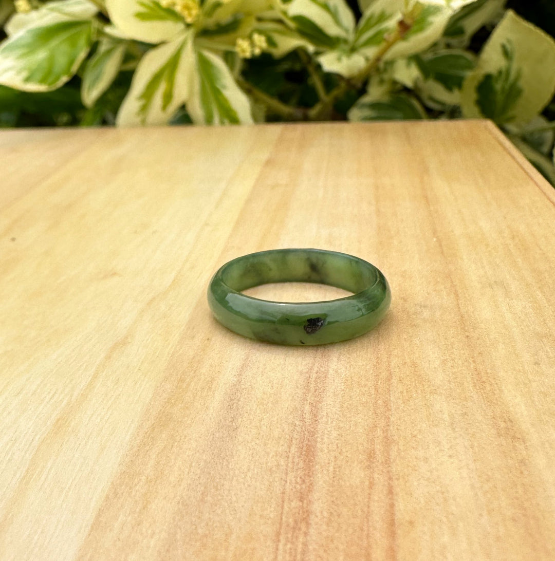 Narrow jade band ring resting on a wooden table with soft natural light