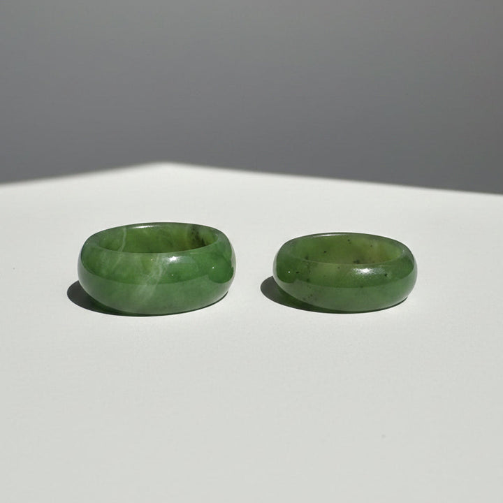 Two green jade rings displayed side-by-side on grey background 8mm vs 10mm