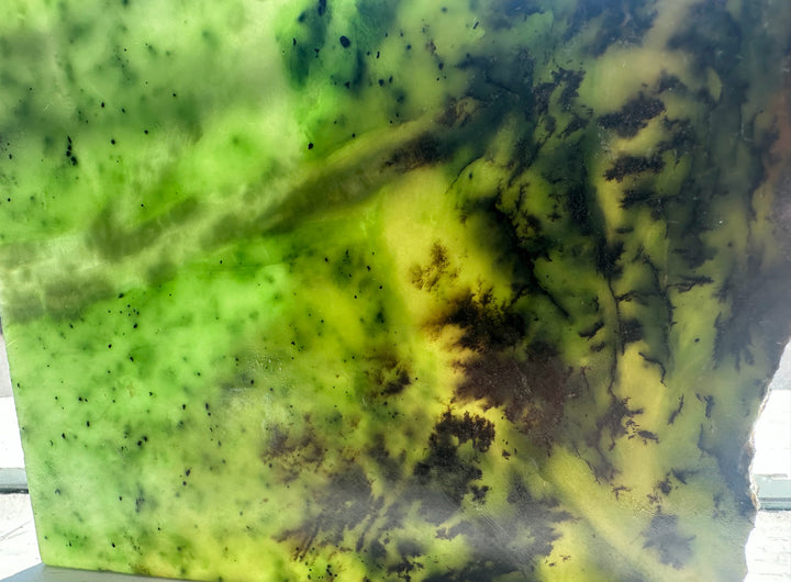 A square stone slab or tile featuring a marbled pattern of vibrant green, yellow, and dark brown/black veins, jade