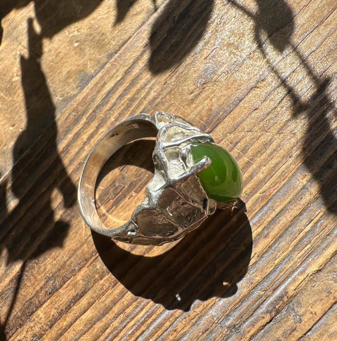 Top view of Jade Hammered Ring featuring a green jade cabochon in a rugged silver setting on a wooden surface.