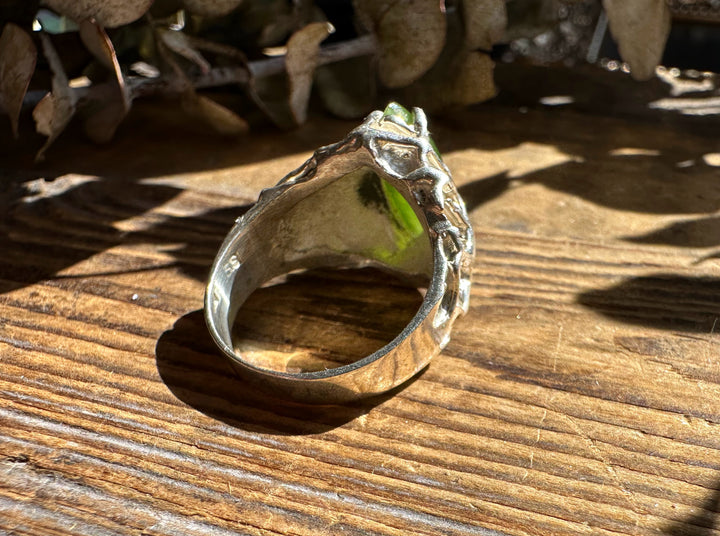 Side view of Jade Hammered Ring showing a rugged silver band and green jade stone on a wooden background.