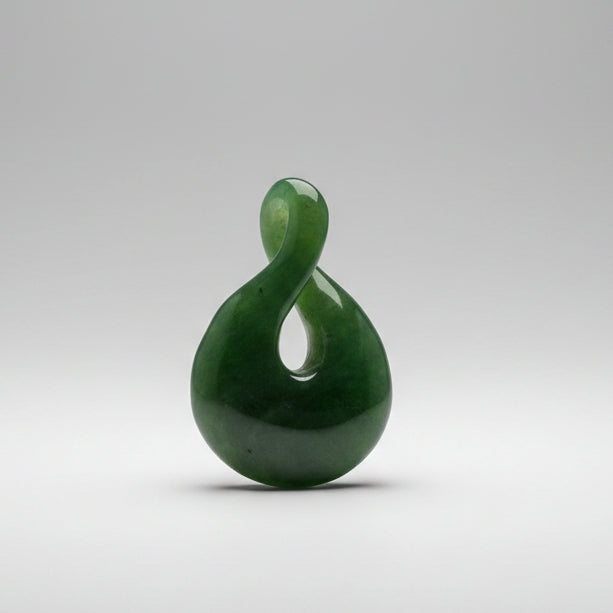 A green polished stone twist pendant, shaped like a infinity on a grey background