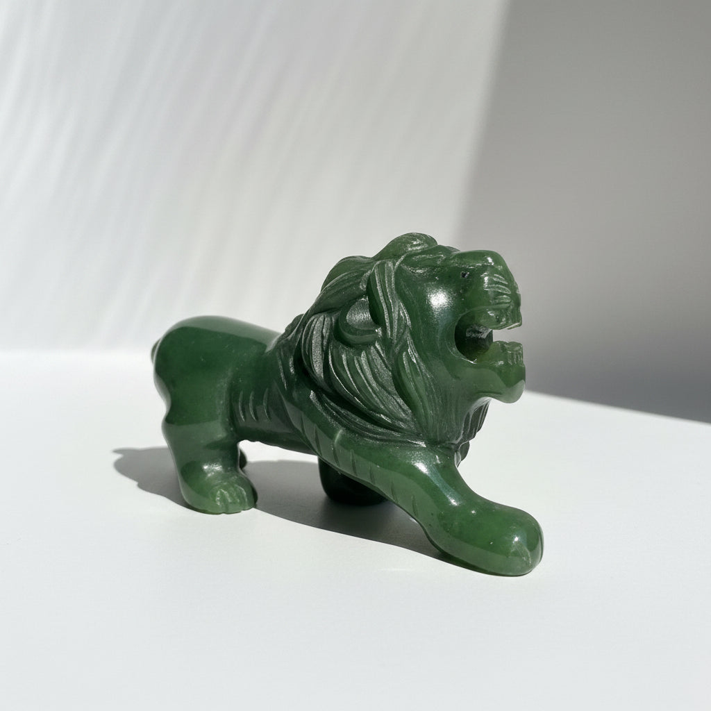 A carved green jade lion figurine with an open mouth, displayed on a light background.