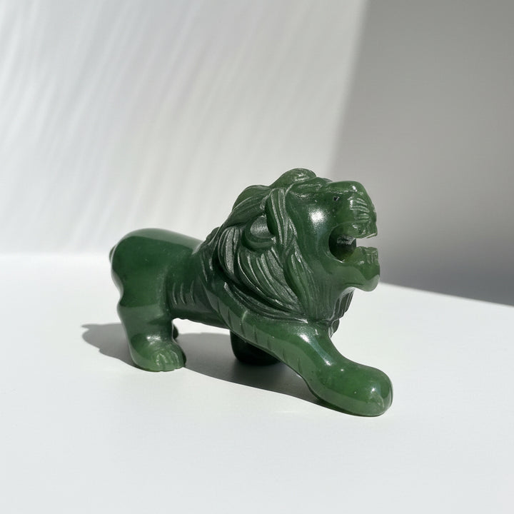 A carved green jade lion figurine with an open mouth, displayed on a light background.