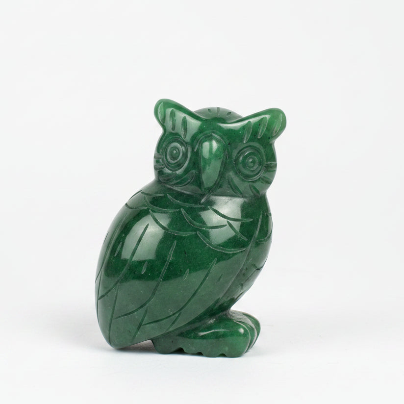 A carved green jade owl figurine sitting on a white background.
