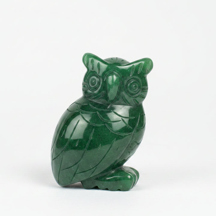 A carved green jade owl figurine sitting on a white background.