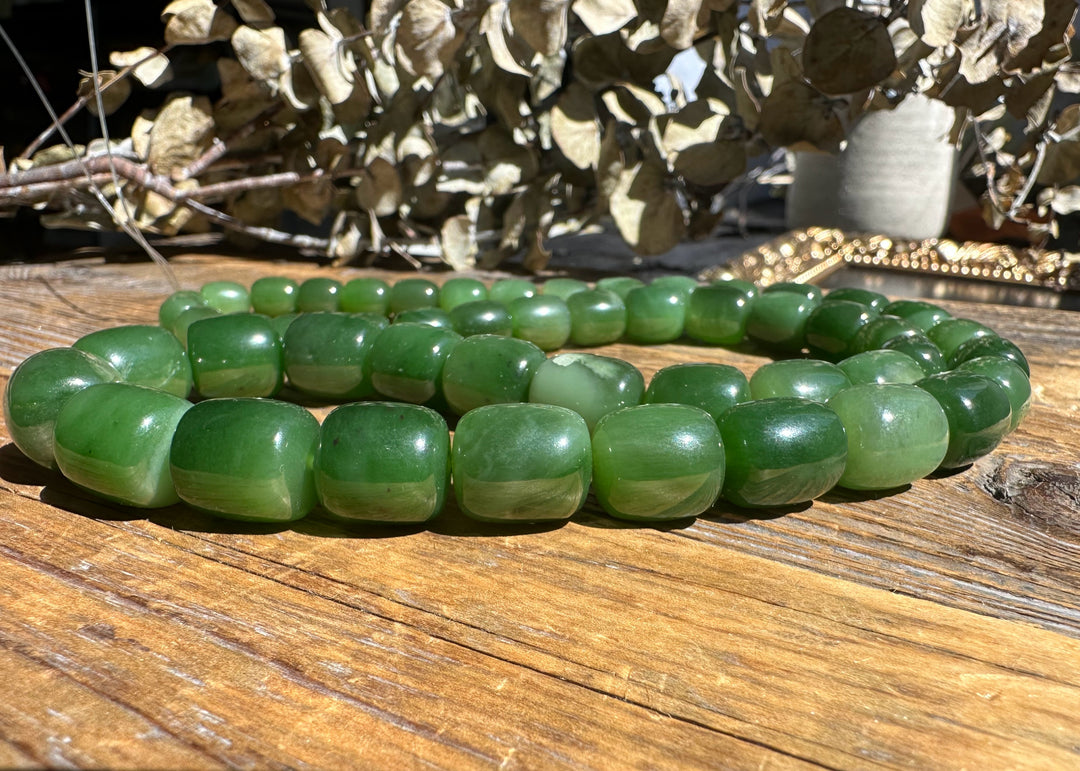 Siberian Jade barrel beads on a wooden surface, 24 inch unstrung strand