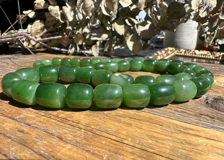 Siberian Jade barrel beads on a wooden surface, 24 inch unstrung strand