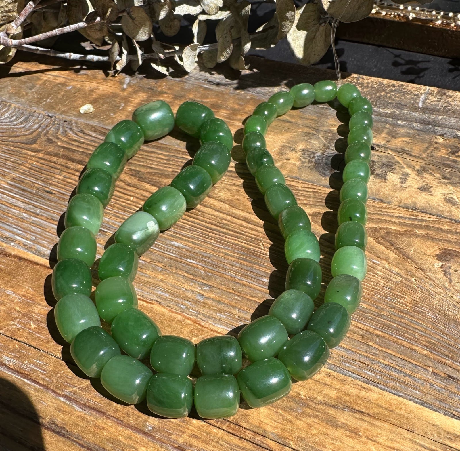 Siberian jade barrel beads on a 24 inch unstrung graduated strand in varying green tones.