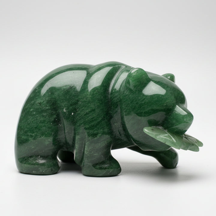 A polished green jade bear figurine holding a fish, displayed white grey background.