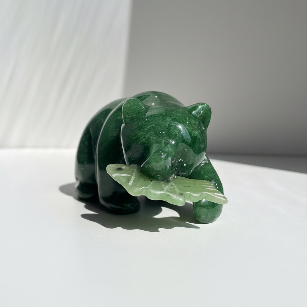 A polished green jade bear figurine holding a fish, displayed on a white background
