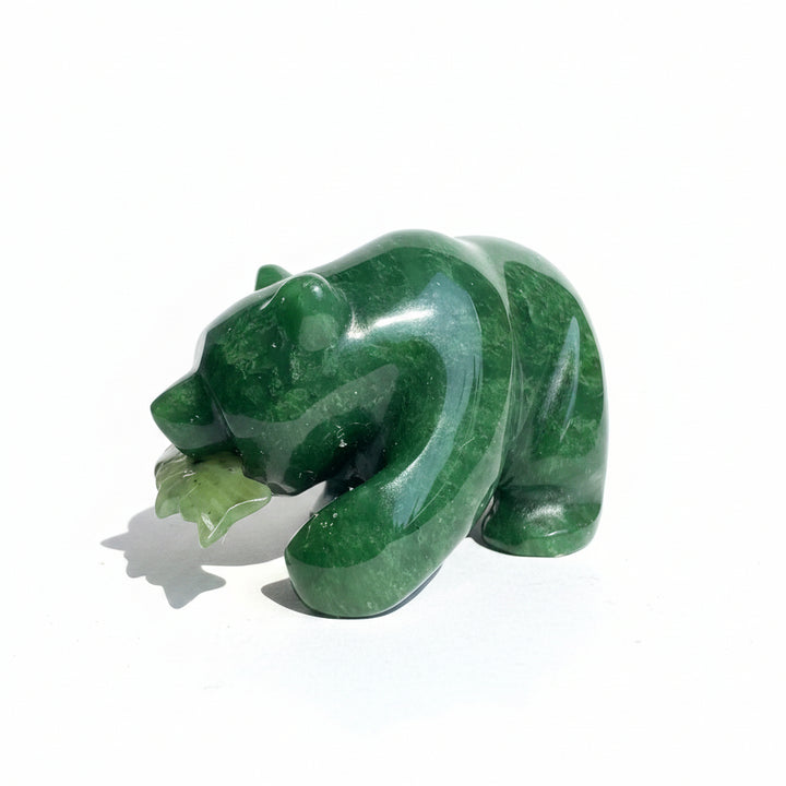 A dark green jade bear with a fish in its mouth on a white background