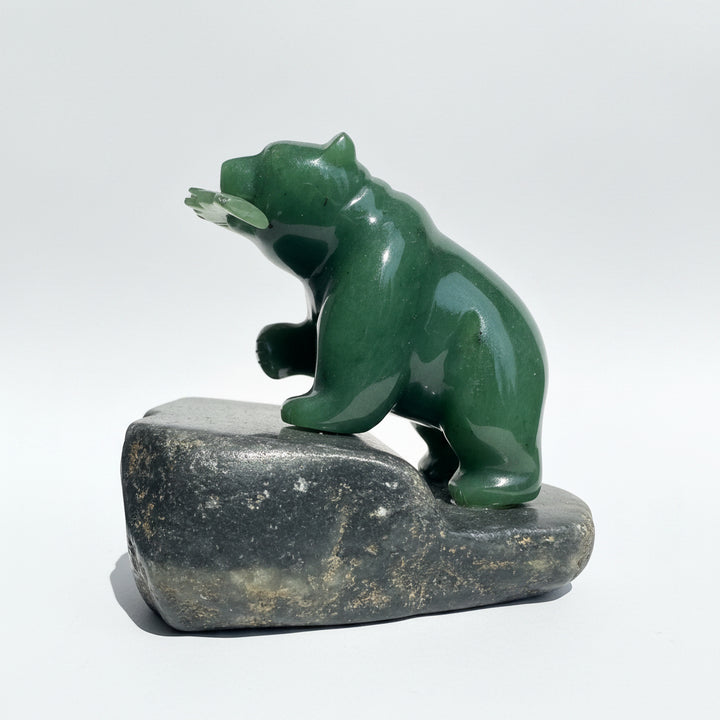 Jade Bear holding a jade fish in its mouth, standing on a granite base, with a white background