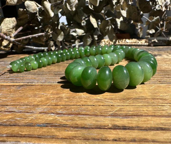 Close up of large green oval Siberian Abacus beads on a wooden surface