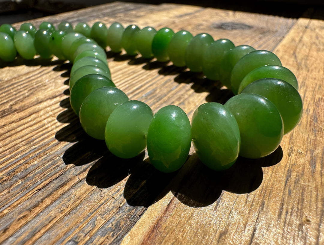 Close up of bright green round Siberian Abacus beads resting on a sunlit wooden surface