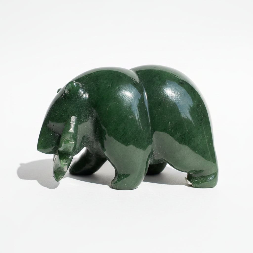 A polished dark green jade bear figurine carved from jade on a white background