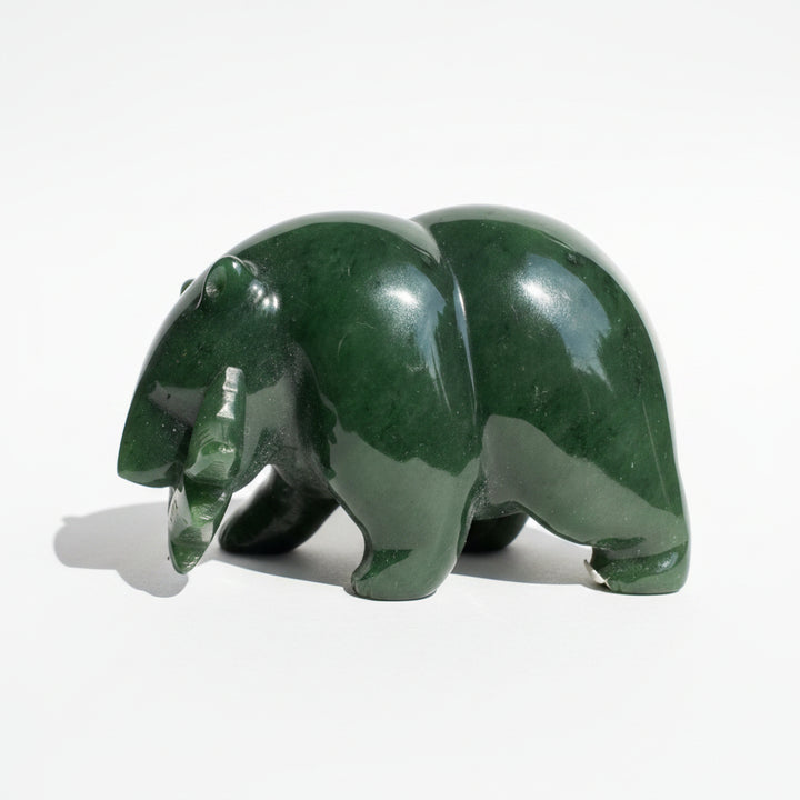 A polished dark green jade bear figurine carved from jade on a white background