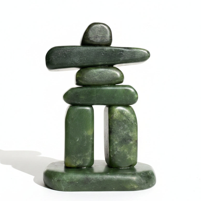 A small green jade inukshuk sculpture standing on a white background.