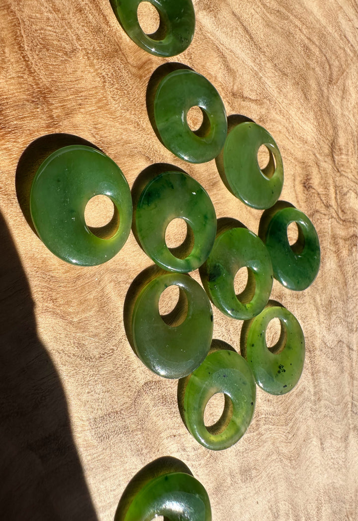 Group of jade circle pendants with holes arranged on a wooden surface