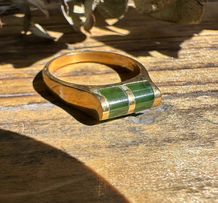 Vintage Jade Ring with two green rectangular inlays set in a gold band on a wooden surface.