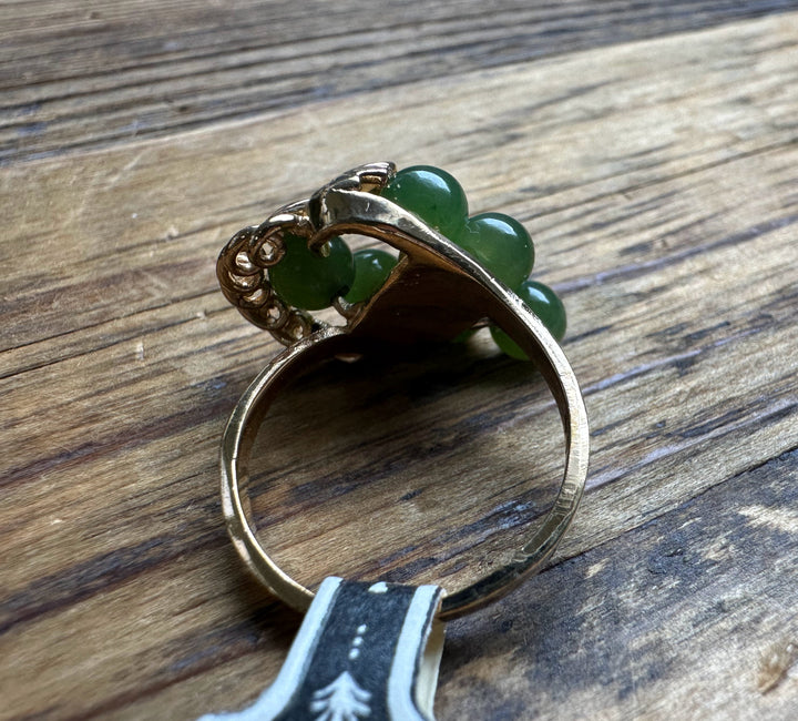 Side view of Vintage Jade Grape Ring showing green jade beads and a gold band on a wood background