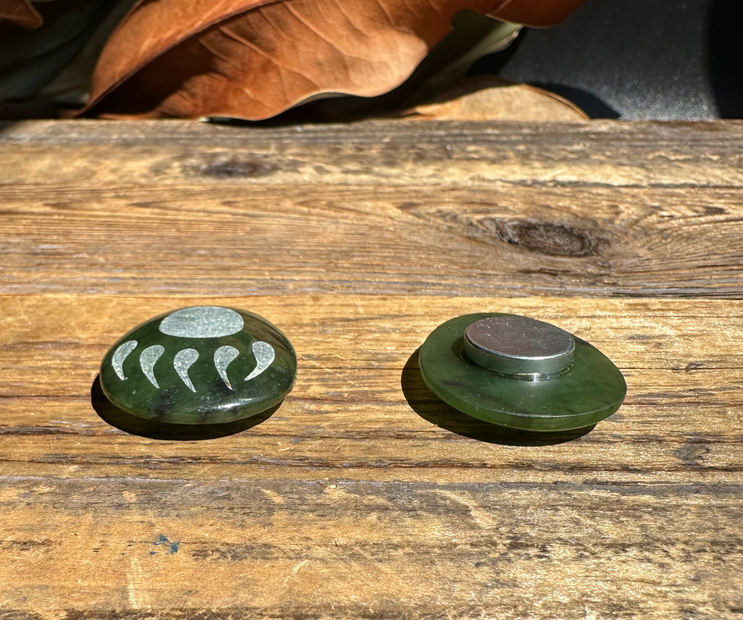 Front and back views of Canadian Jade Bear Paw Magnet on wood surface showing the green oval front with paw design and the metal backing