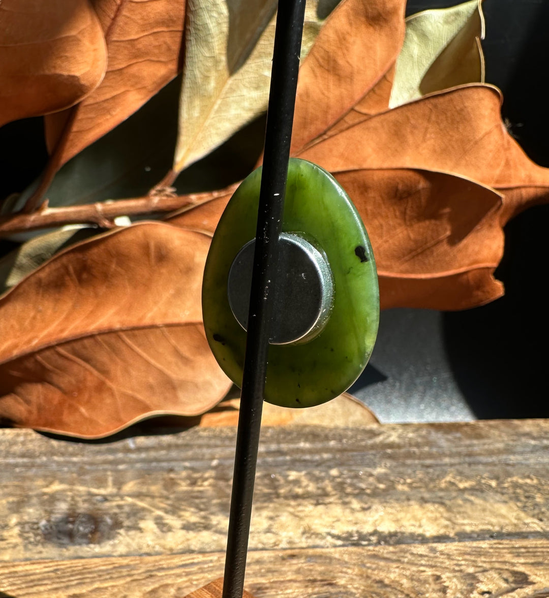 Back view of green jade bear paw magnet with circular metal backing
