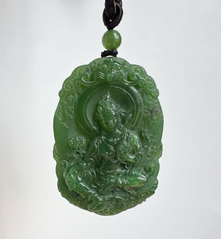 Green jade Guanyin pendant with a carved figure on a circular medallion, hanging from a black cord
