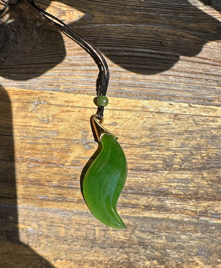 Green curved nephrite jade pendant with a gold bail on a black cord