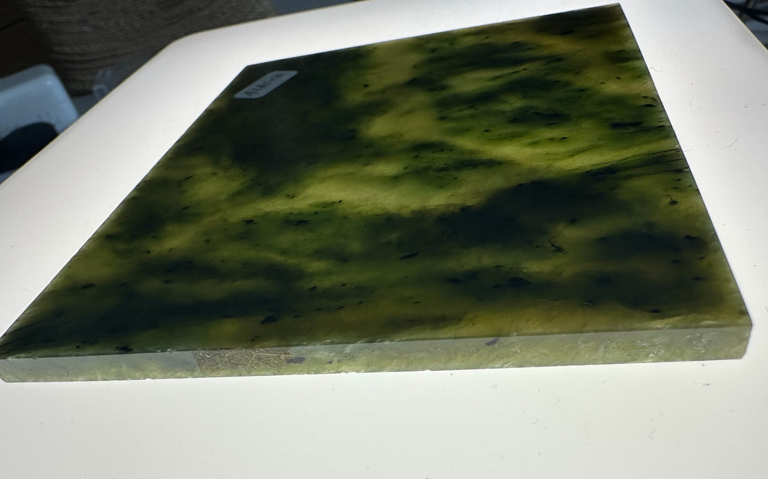 A square slab of natural jade with a mottled green and yellow pattern, displayed on a white surface.