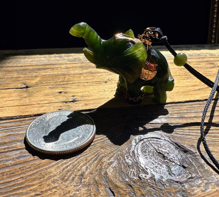 Green jade elephant pendant on a leather cord with brass accents beside a quarter for scale.