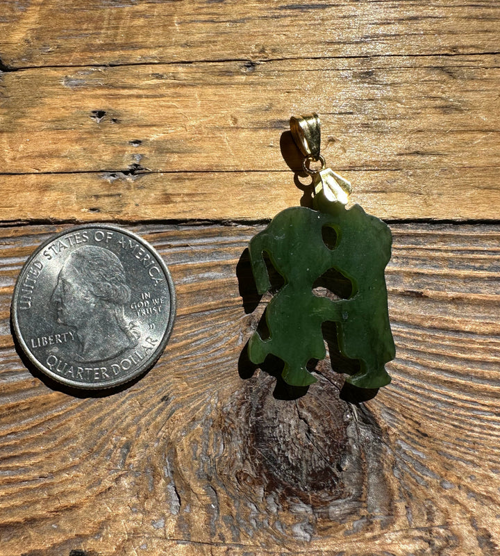 Green jade elephant pendant with gold bail beside a quarter on a weathered wooden surface.