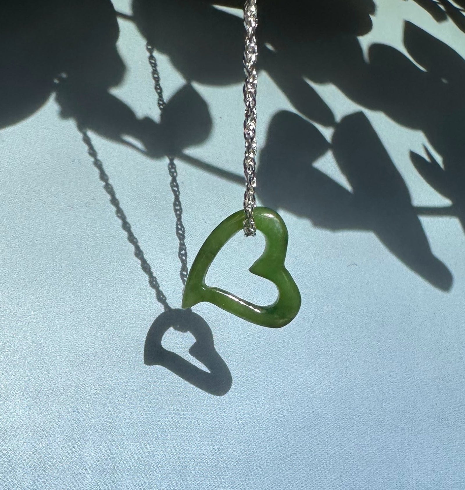 Floating jade heart pendant with two hearts on a silver chain a solid larger heart and a smaller hollow heart